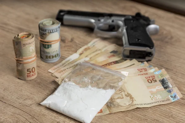 Geld, drugsand een kanon op een houten tafel — Stockfoto