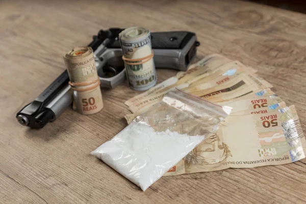 Geld, drugsand een kanon op een houten tafel — Stockfoto