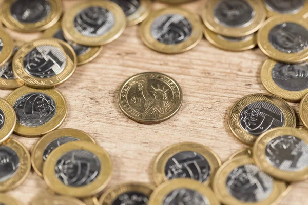 Monedas de 1 dólar en medio de varias monedas reales en una madera — Foto de Stock