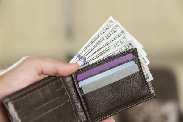 Бумажник со 100 долларовыми купюрами в руке мужчины — стоковое фото