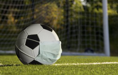 Futbol topu maske takıyor, spor konsepti COVID-19 salgınından muzdarip..