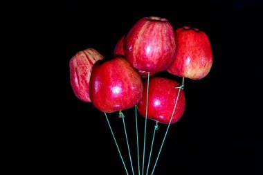 Siyah arka planda ve düşük ışıkta yüzen balonlar gibi yüzen elmalar grubu.