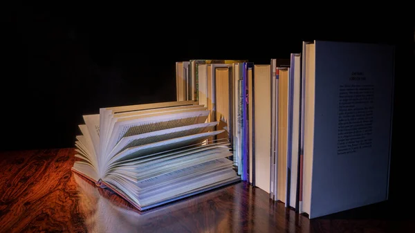 光线昏暗地把一堆堆书放在一张旧桌子上 — 图库照片