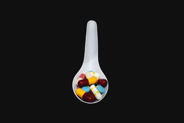 Group of pills in spoon on dark background — Stock Photo, Image