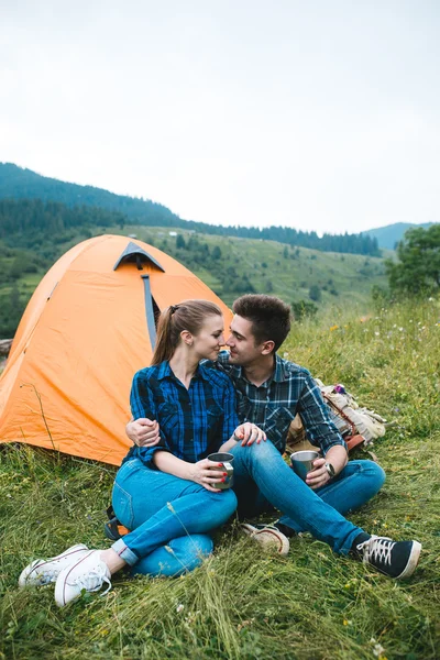 Fiú és lány szerelmesek turisták lazítson és csodálja meg a gyönyörű hegyi táj — Stock Fotó