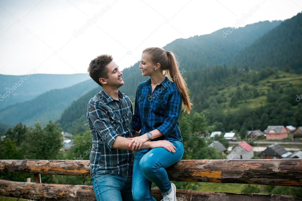 Guy and girl lovers tourists relax and admire beautiful mountain scenery
