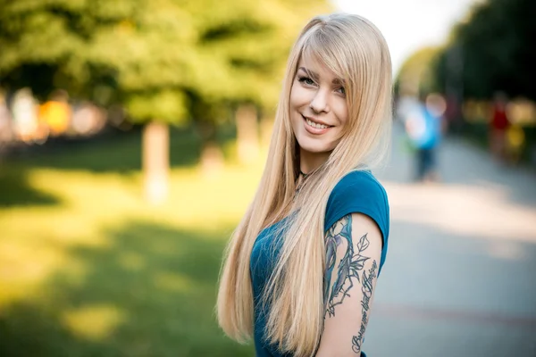 Портрет красивой молодой блондинки с длинными волосами и милой улыбкой на открытом воздухе — стоковое фото