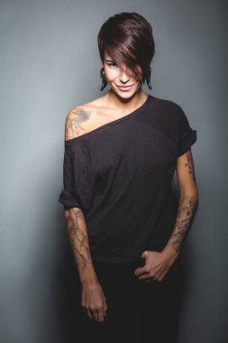 Güzel esmer kadın dövme ve Studio koyu arka plan üzerinde poz bir spor rakam ile