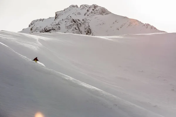 Männlicher Snowboarder beim Snowboarden auf Neuschnee auf der Skipiste am sonnigen Wintertag im Skigebiet in Georgien — Stockfoto