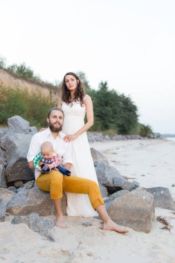 Sahilde bir çocukla genç güzel aile. Erkek ve kadın bebekle içinde mutlu yaz tatillerini üzerinde rahatlatıcı seviyorum. Seyahat tatil kavramı.