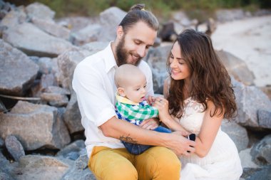Sahilde bir çocukla genç güzel aile. Erkek ve kadın bebekle içinde mutlu yaz tatillerini üzerinde rahatlatıcı seviyorum. Seyahat tatil kavramı.