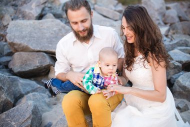 Sahilde bir çocukla genç güzel aile. Erkek ve kadın bebekle içinde mutlu yaz tatillerini üzerinde rahatlatıcı seviyorum. Seyahat tatil kavramı.