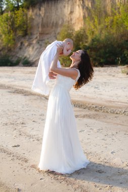 Sahilde denizin kucağında bir bebek tutan genç bir anne