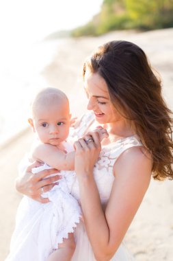 Sahilde denizin kucağında bir bebek tutan genç bir anne
