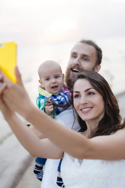 Young beautiful family with a child on the beach. Man and woman with baby happy in love relaxing on summer holidays. Travel vacation concept. — Stock Photo, Image