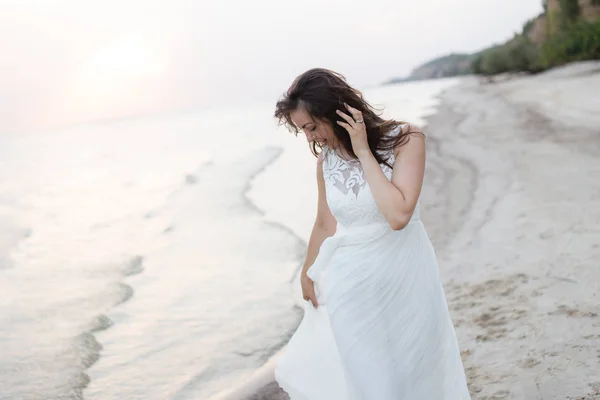 Mulher morena jovem bonita em vestido longo branco na costa do mar — Fotografia de Stock