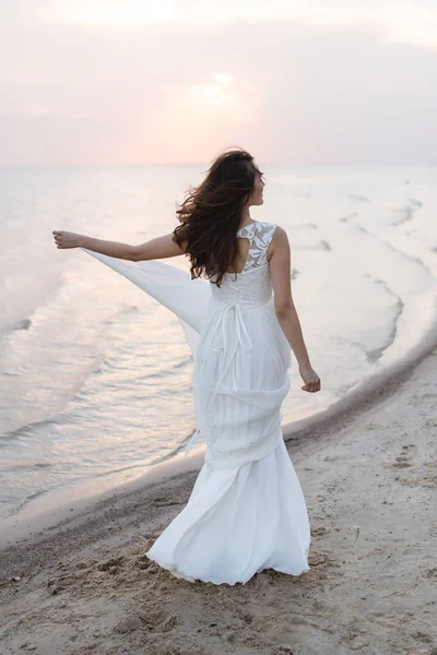 Vacker ung brunett kvinna i vit lång klänning vid havet — Stockfoto