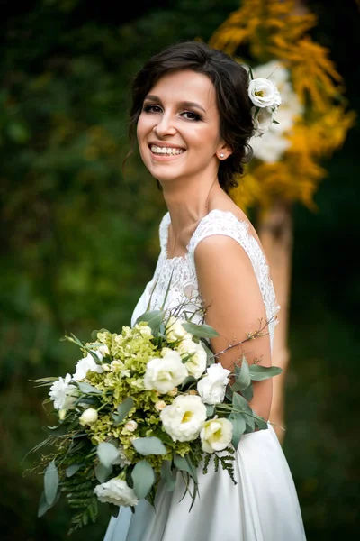 Portret van de mooie bruid in trouwjurk met een mooi boeket bloemen — Stockfoto