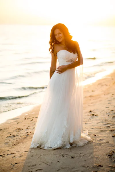 Портрет брюнетки невесты в свадебном платье с красивой прической, вуалью и макияжем на берегу моря — стоковое фото