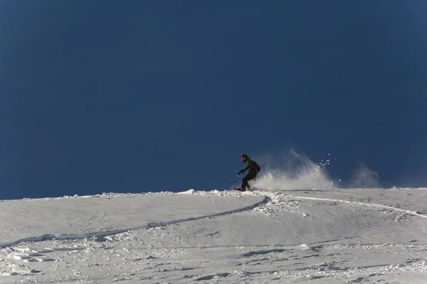 Snowboardzista, snowboard na świeżym śniegu na stoku narciarskiego na słoneczny zimowy dzień w ośrodku narciarskim w Gruzji — Zdjęcie stockowe