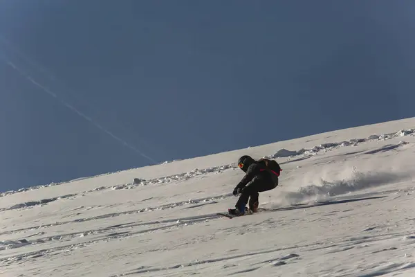 Snowboarder snowboarding on fresh snow on ski slope on Sunny winter day in the ski resort in Georgia — Stok Foto