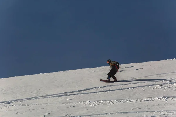 Snowboarder snowboard en nieve fresca en pista de esquí el soleado día de invierno en la estación de esquí de Georgia — Foto de Stock