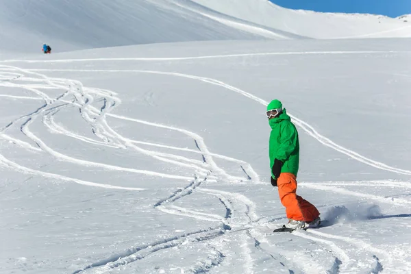 Snowboarder snowboard en nieve blanca fresca con pista de esquí en el soleado día de invierno —  Fotos de Stock