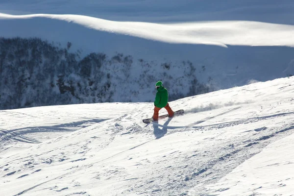 Snowboarder snowboard en nieve blanca fresca con pista de esquí en el soleado día de invierno —  Fotos de Stock