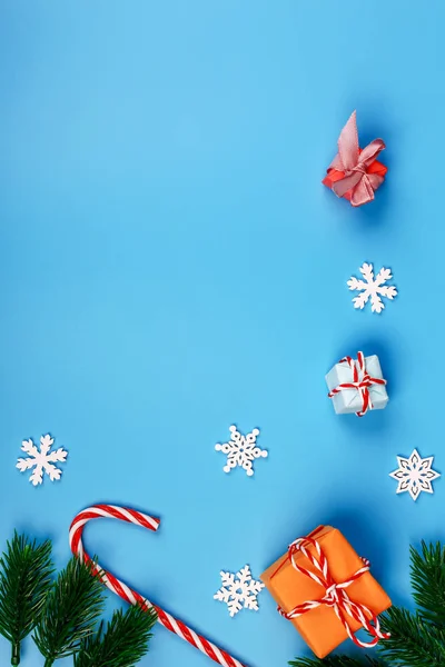 Noel arkaplanı. Hediye kutusu. Firavun dalı ve konisi. Kar taneleri. Lolipop. Mavi arka plan. Üst Manzara. Yakın plan..