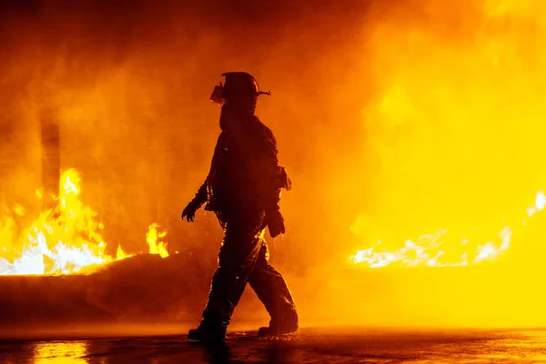 Jefe de bomberos caminando frente al fuego durante el ejercicio de extinción de incendios — Foto de Stock