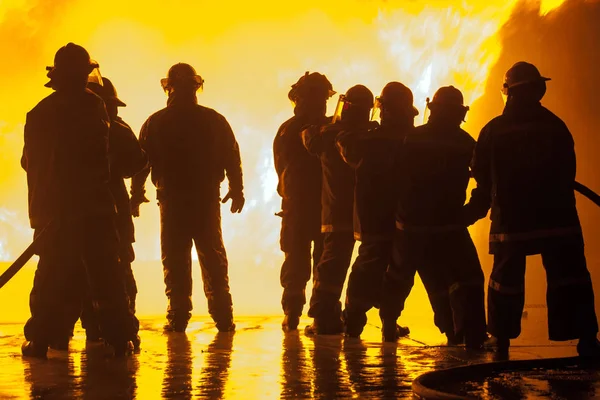 Group of eight firefighters during fire fighting exercise — Stock Photo, Image