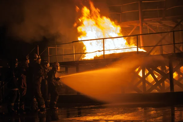 Пожарные поливают горящую конструкцию во время учений Лицензионные Стоковые Фото