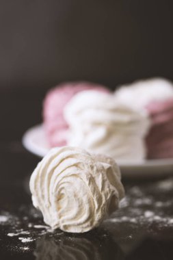 Siyah arka planda beyaz ve pembe şekerlemeler.