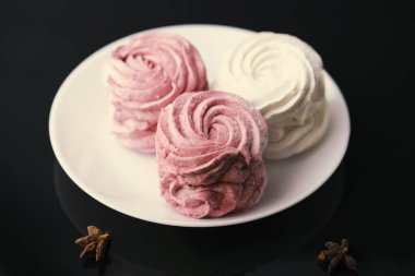 Siyah arka planda beyaz ve pembe şekerlemeler.