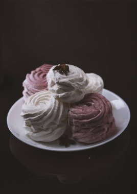 Siyah arka planda beyaz ve pembe şekerlemeler.