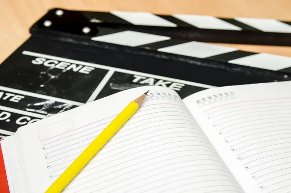 Palmas de filme com bloco de notas e caneta na mesa de madeira — Fotografia de Stock