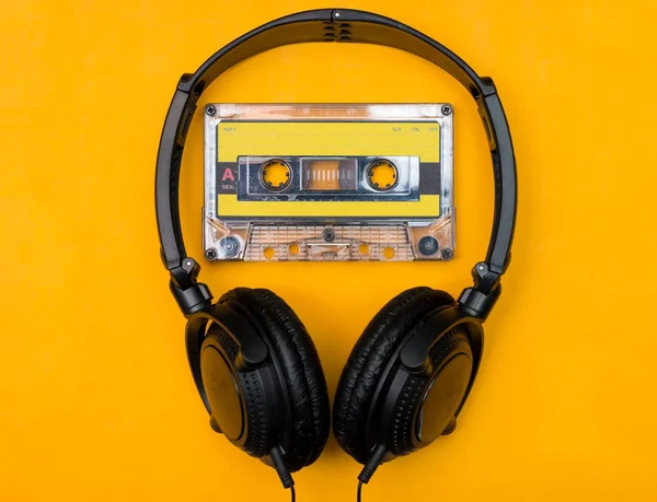 Sluchátka a audio kazeta na žlutém podkladu — Stock fotografie
