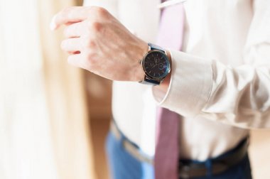 Beyaz gömlekli bir adam saatini ayarlar.