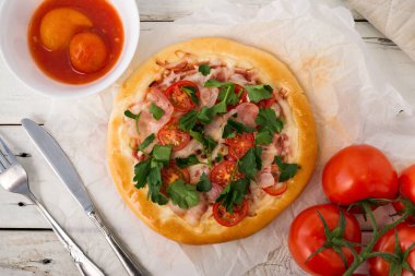 Ev yapımı kır pizzası, çatal bıçaklı ve domatesli.