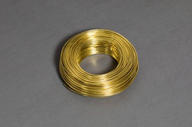 Gri arka planda altın kablo yuvarlanıyor. Metal bir iplik dalgası. Yüksek çözünürlüklü fotoğraf..