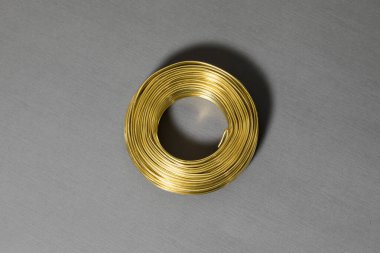 Gri arka planda altın kablo yuvarlanıyor. Metal bir iplik dalgası. Yüksek çözünürlüklü fotoğraf..