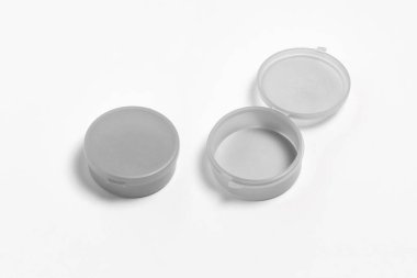 Boş ve kapalı plastik kutular, beyaz arkaplanda izole edilmiş. Tasarımınız için plastik kap ya da aksesuar paketi. Yuvarlak teneke. Yüksek çözünürlüklü fotoğraf. Üst görünüm