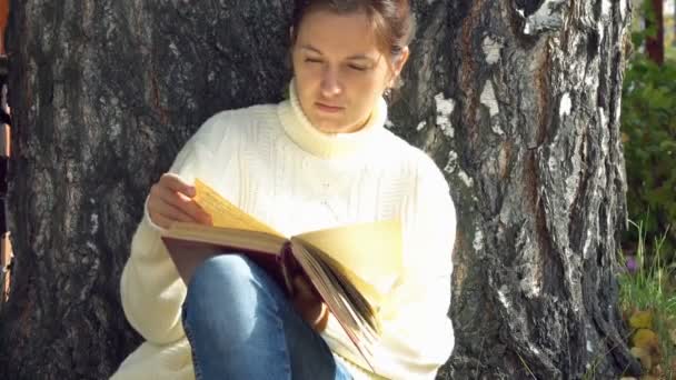 Junge schöne Frau liest im Park ein Buch — Stockvideo