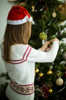 Kırmızı şapkalı esmer kız Noel ağacı süsle