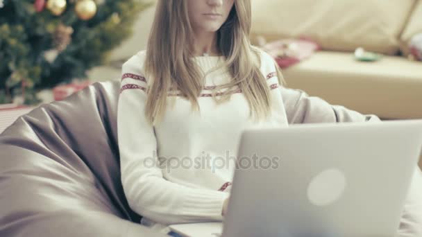 Girl in christmas cap using laptop on soft chair — Stock Video