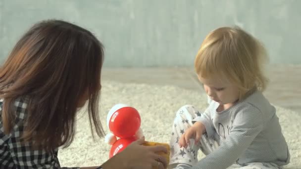 Mutter spielt mit kleinem Mädchen mit Klötzen und Puppe auf Teppich — Stockvideo