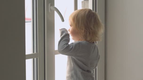 Lilla baby flicka stående nära fönstret och känslomässigt gestikulerar — Stockvideo