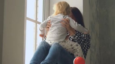 Küçük bebek kızı pencerenin yakınındaki anne çalış