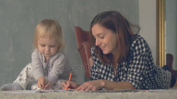 Mother and her little daughter are drawing with pencils in album — Stock Video