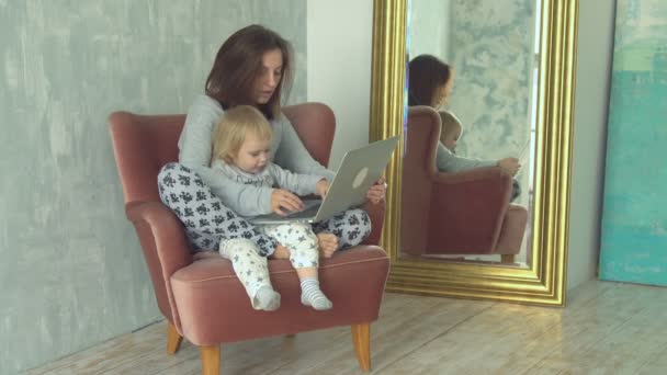 Vacker mor med laptop med liten bebis på hennes knän — Stockvideo